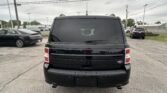 Rear view of a black Ford SUV in a parking lot, other cars visible nearby, with power lines overhead and a cloudy sky