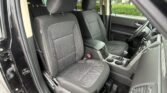 Front seats of a black cloth-upholstered SUV interior, center console with cup holders and gear shifter visible in the foreground.