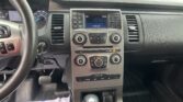 Dashboard interior viewed from the driver’s seat showing the center infotainment screen, radio controls, and climate dials with a gear shifter below.