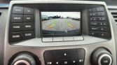 In-dash rear-view camera display showing parking guidance lines (green/yellow/red) over a parking lot scene.