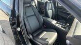 Interior of a black car showing front and rear leather seats, center console, and gear shifter with the door open on the driver's side