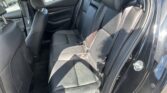 Rear seating area of a black car with leather upholstery, showing three headrests and three-point seat belts