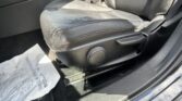 Close-up of a black leather car seat and center console area, with a visible seat belt buckle and floor mat nearby.