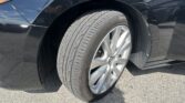 Close-up of a black car’s front wheel well with a Hankook tire and silver alloy rim
