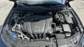 Open hood view of a Mazda engine bay, showing the SKYACTIV-G engine cover, battery, and various hoses and components in the foreground.