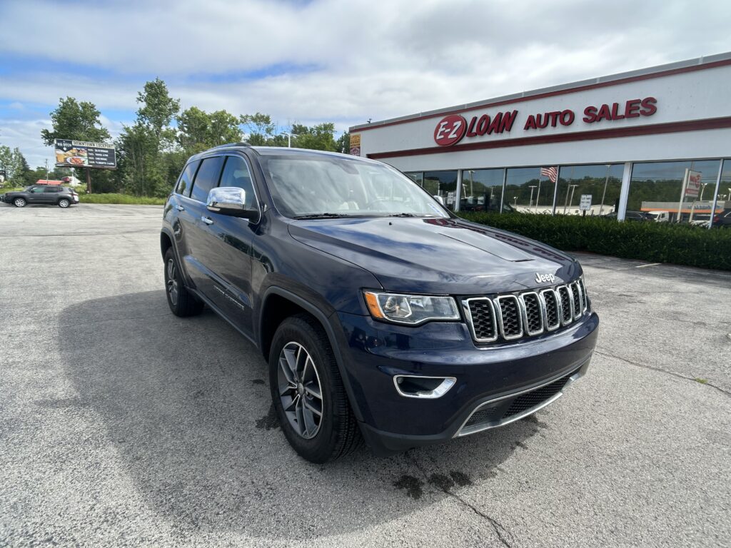 Dark blue Jeep SUV in a parking lot with an E-Z Loan Auto Sales storefront in the background.
