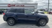 Close-up side view of a dark blue SUV parked in front of the E-Z LOAN Auto Sales storefront.