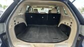 Open SUV trunk with folded beige rear seats and a black rubber cargo mat, view from the tailgate in daylight.