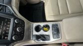Beige leather car interior with center console, cupholders, gear shifter, and part of the passenger seat visible.