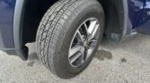 Close-up of a car tire mounted on a blue SUV, showing the tread pattern and alloy wheel