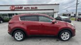 Red SUV parked in front of a white dealership building with a red E-Z LOAN AUTO SALES sign and large windows, under a cloudy sky, with other cars in the lot nearby.