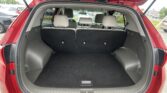 Open hatch of a red SUV showing a spacious cargo area with rear seats upright and gray upholstery inside.