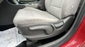 Front interior of a red car with light gray fabric seats, center console, and gear shifter.