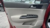 Interior of a car door panel with window controls, view of a parking lot seen through the open window and side mirror.