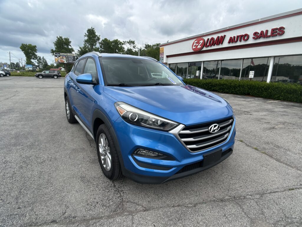 Blue Hyundai SUV parked in front of EZ Loan Auto Sales showroom on a cloudy day.