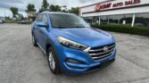 Blue Hyundai SUV parked in front of EZ Loan Auto Sales showroom on a cloudy day.