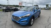 Blue Hyundai SUV parked in a car lot with other vehicles and a large EZ Loan Auto Sales sign in the background under a cloudy sky