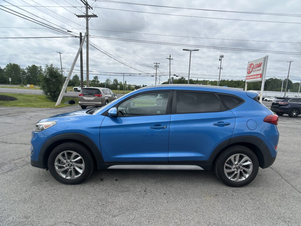 Blue SUV in the foreground of a dealership lot, with a cloudy sky, power lines, and an EZ Loan Auto Sales sign in the background.