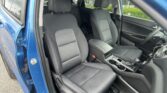 Open blue car door reveals front seats in dark gray fabric, center console, and steering wheel visible inside the cabin.