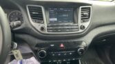Car infotainment screen displaying FM radio (104.9) with surrounding control buttons and vents in a vehicle dashboard accessory panel
