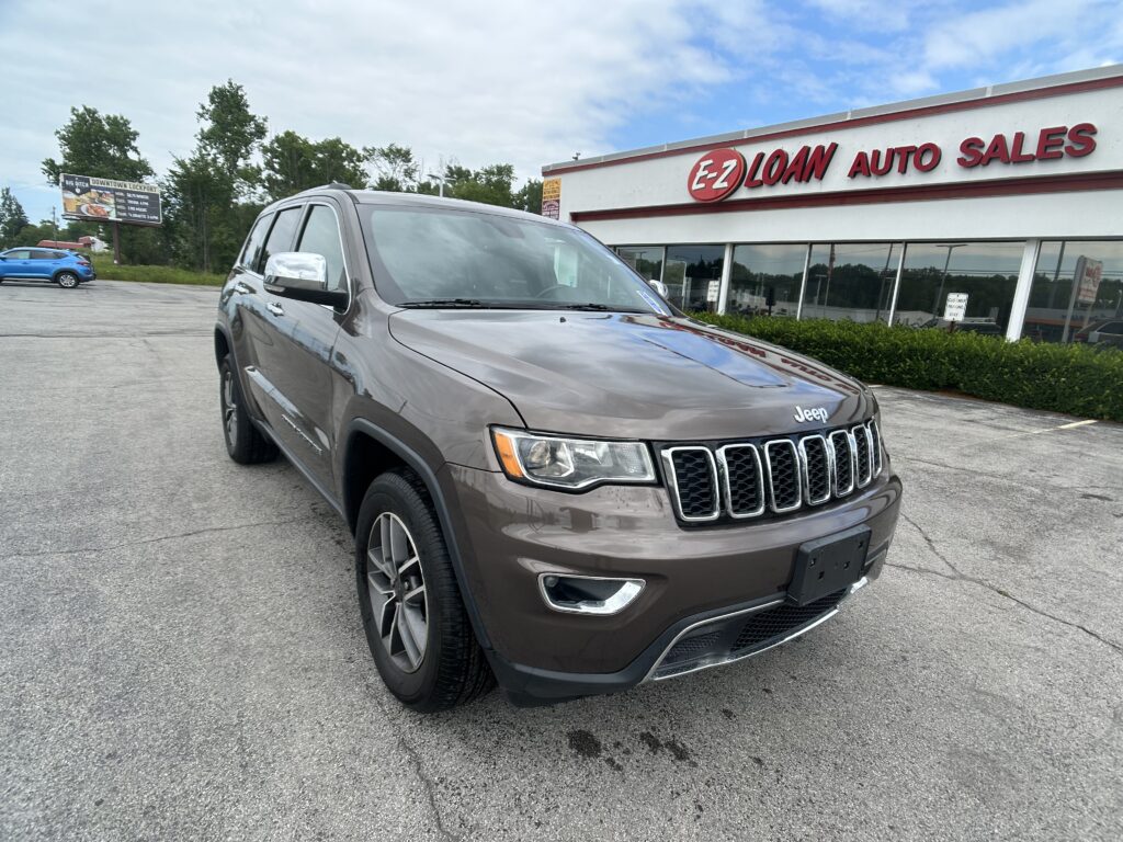 Front-right view of a gray Jeep SUV parked in a dealership lot with EZ Loan Auto Sales building in the background.