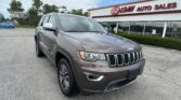 Front-right view of a gray Jeep SUV parked in a dealership lot with EZ Loan Auto Sales building in the background.