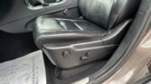 Close-up of a black leather front seat and center console with gear selector, seat belt, and Jeep logo on the door sill.