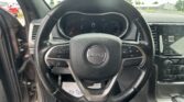 Steering wheel of a Jeep with instrument cluster and center touchscreen visible in the dashboard