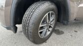 Close-up of a car tire and alloy wheel inside the front wheel well of a gray SUV.