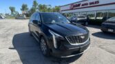 Front view of a dark Cadillac SUV parked in a lot in front of EZ Auto Sales on a sunny day.