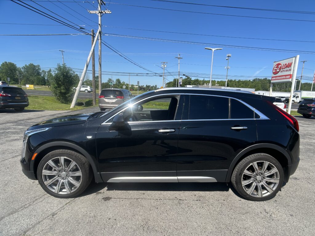 Close-up side view of a black SUV in a parking lot with power lines and a red EZ Loan Auto sign in the background
