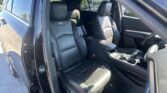 Interior of a black car showing front leather seats, center console, and an open rear door on a sunny day.