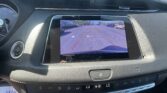 Car interior dashboard with a rearview camera display showing parking guide lines in a parking lot during daylight