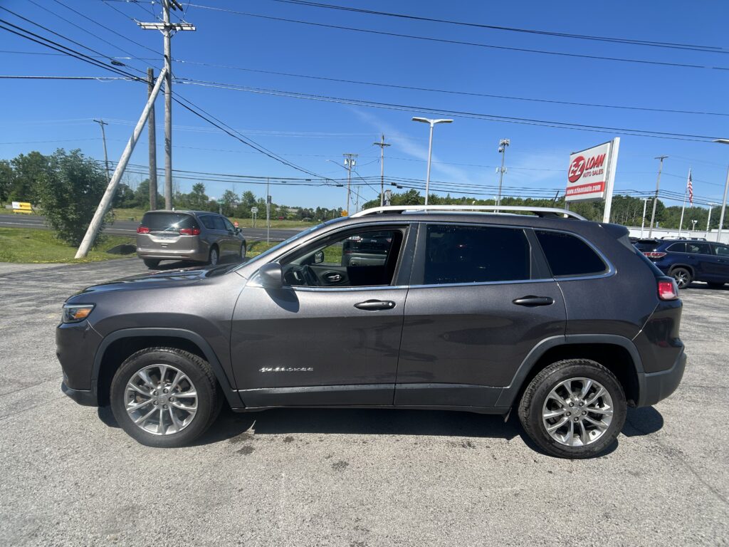 Gray SUV parked in a dealership lot on a sunny day, with tall power lines and an EZ Loan Auto Sales sign in the background.