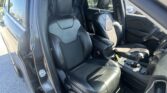 Open-door view of a black leather car interior showing the front seats and center console with gear shifter visible