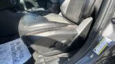 Interior of a black leather car: front passenger seat, center console, and door panel visible from the open driver-side area.