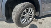 Close-up of a car tire and alloy wheel in the wheel well, with dirt on the body panel nearby.