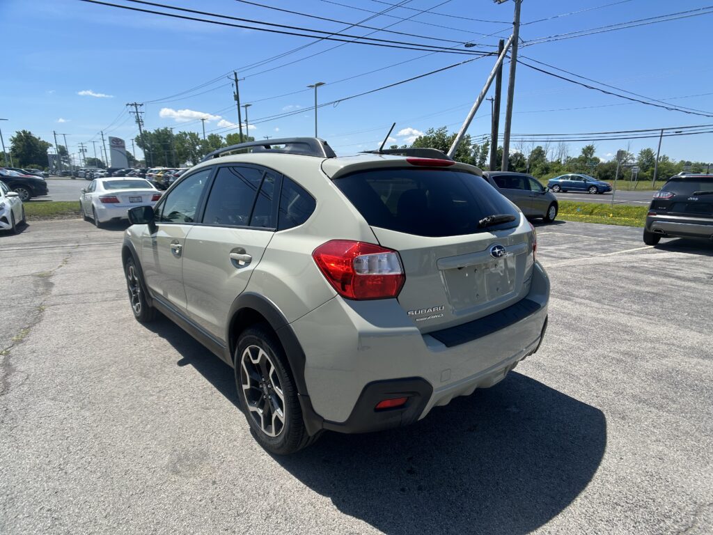 White Subaru SUV in a parking lot, with other cars and blue sky overhead; power lines visible in the background.