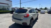 Silver Subaru Crosstrek in the foreground of a dealership lot with a Toyota dealership building in the background.