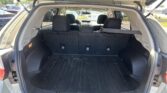 SUV cargo area with rear seats upright; view from tailgate, black rubber mat, and surrounding parking lot vehicles visible outside.