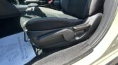 Front passenger seat and center console of a car interior, with visible seat belt buckle and orange stitching on dark upholstery.