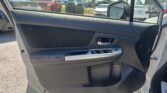View from inside a car looking out the passenger-side door at a busy dealership lot with many parked vehicles nearby.