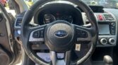 Close-up view of the steering wheel from the driver’s seat, with the instrument cluster and center console visible and a parking lot outside the windshield.