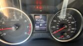 Dashboard close-up showing tachometer (left) and speedometer (right) with a central display reading 'P' and mileage; red seatbelt and door warning lights are lit.