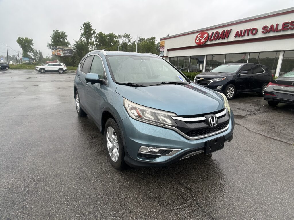 Blue Honda SUV in the foreground of a rainy dealership lot, with EZ Loan Auto Sales signage on the building to the right and other cars in the background.