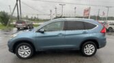 Close-up side view of a blue SUV parked in a wet parking lot, with overcast skies and power lines in the background.