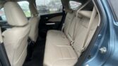 Rear passenger seats in a beige leather SUV, rain on the windows outside