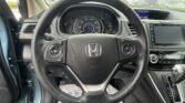 Close-up of a Honda steering wheel and instrument cluster inside a parked car, with a rainy windshield and center display in view.