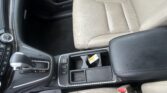 Beige perforated leather car seat with a black center console, gear shifter, and cup holder area in view.