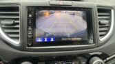 In-dash rearview camera display with yellow parking guide lines over a wet parking lot behind the car.